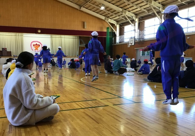 頑張って跳ぶ２年生と記録を数える５年生